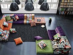 a living room filled with lots of different colored couches and pillows on the floor