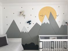 a baby's room with mountains painted on the wall and a crib bed