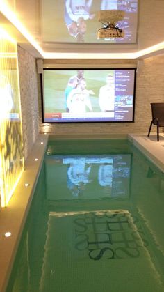 an indoor swimming pool with tvs on the wall