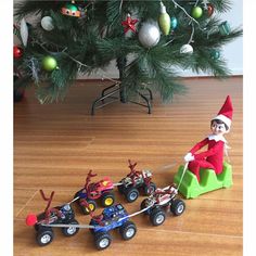 an elf is riding on a toy truck with two children in it and pulling the car behind him