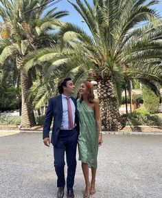 a man and woman standing in front of palm trees