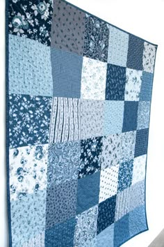 a blue and white quilt hanging on the wall