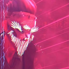 a man wearing a red mask with lightning streaks on his face in front of a pink background