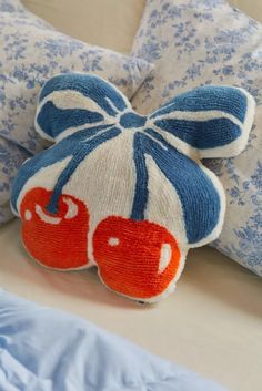 a close up of a stuffed animal on a bed with blue and white pillows in the background