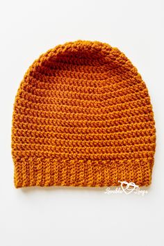 an orange knitted beanie sits on a white surface