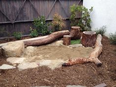 a wooden bench sitting in the middle of a dirt field next to a tree stump