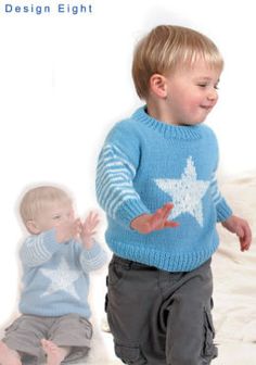 a young boy wearing a blue sweater and gray pants, standing next to another toddler