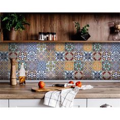 a kitchen counter with apples and spices on it, next to a wooden shelf filled with bottles