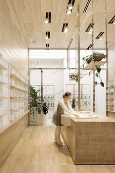 a woman standing in front of a counter with a plant on it and shelves behind her