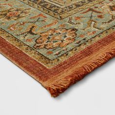 an orange and blue rug with fringes on the bottom is laying on a white surface