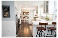 a kitchen with three stools in front of the counter and an open floor plan