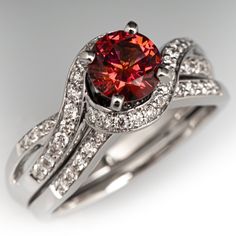 a ring with a red diamond surrounded by white diamonds on top and bottom, in the shape of a heart