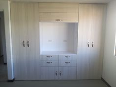 an empty room with white cupboards and drawers on the wall next to each other