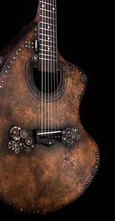 an old, worn out guitar with gears on it's back and neck is shown