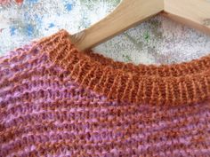 an orange and purple sweater hanging on a wooden hanger