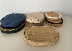 four round woven baskets sitting on top of a white table next to each other,