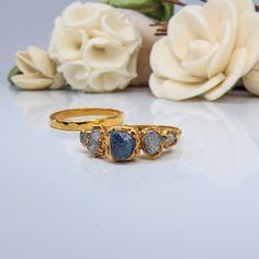 three stone ring sitting on top of a table next to flowers