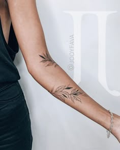 a woman's arm with a feather tattoo on the left forearm and right arm