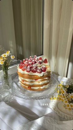 a cake sitting on top of a glass plate covered in frosting and strawberries