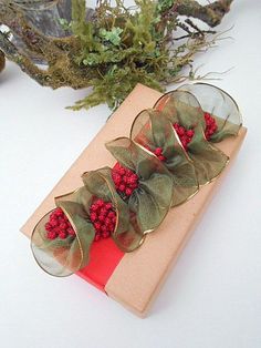 a present wrapped in brown paper with red berries and green leaves sitting on top of it