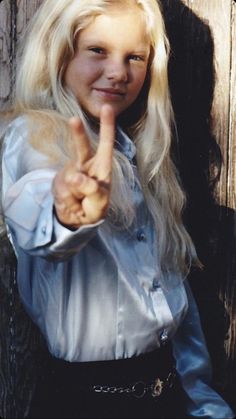 a woman with long blonde hair pointing to the side