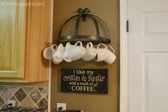 coffee mugs are hanging from a rack in the kitchen with a sign above it