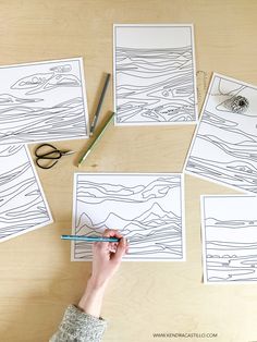 someone is drawing waves on paper with pencils and crayon pens while another person holds a pair of scissors