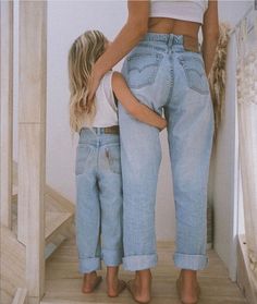 two women standing next to each other in jeans