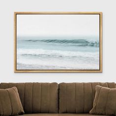 a living room scene with focus on the couch and ocean waves in the frame hanging above it