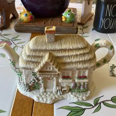 a ceramic teapot with a house on it