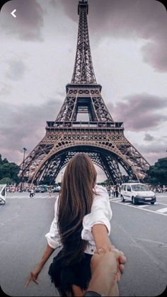 a woman holding the hand of a man in front of the eiffel tower