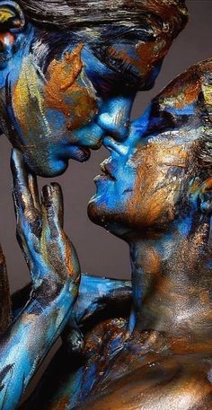 two people covered in blue and gold are touching each other's faces with their hands