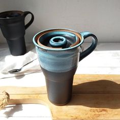 two coffee mugs sitting on top of a wooden cutting board next to each other