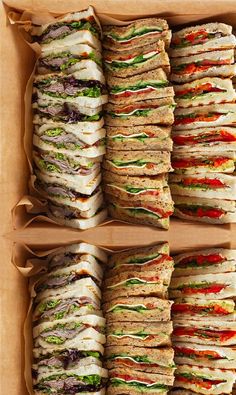 a box filled with lots of different types of sandwiches on top of each other in it