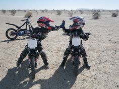 two motorcyclists in full gear standing on dirt with their bikes facing each other