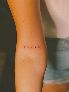 a woman's arm with the word brave tattooed on her left side ribcage