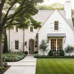 a white house with lots of windows and trees in the front yard is featured on pinterest