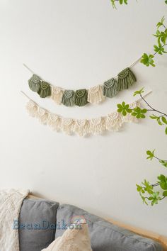 three green and white tasselled garlands hanging on the wall above a couch