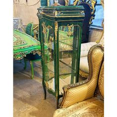 an antique green glass cabinet with gold trimmings and ornate carvings on the doors