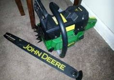 a john deere snow blower sitting on the floor next to a ski pole