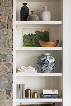 a white shelf with vases and books on it