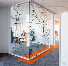 an office cubicle with glass walls and orange flooring