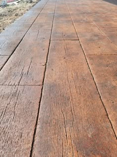 an old wooden bench sitting on the side of a road next to a building and grass