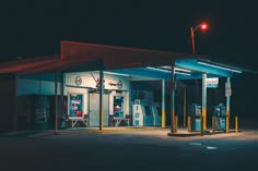 an empty gas station at night with the lights on and no one around it,