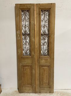 two wooden doors with decorative glass panels on the front and back sides, against a white wall