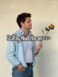 a man standing next to a white wall holding a flower in one hand and the words still by nail horan > > > > > >