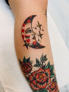 a woman's arm with a tattoo on it that has a crescent moon and flowers