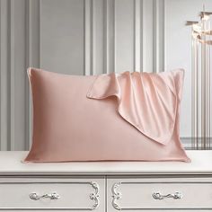 a pink pillow on top of a white dresser