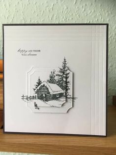 a handmade card with a house and trees in the background on a wooden table