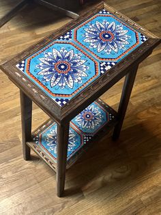 a wooden table with blue and orange tiles on it's sides, sitting on a hard wood floor